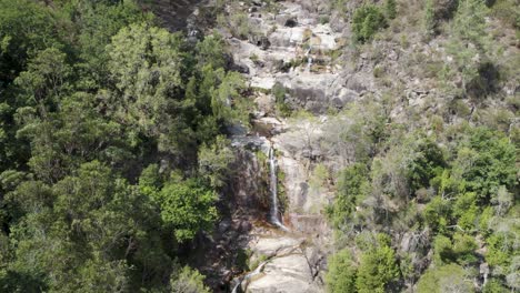 Aerial-view-over-gerês-national-park,-waterfall-cascade,-flowing-down-rock-hill,-Portugal