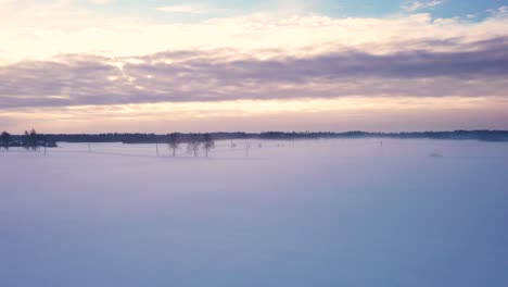 Car-driving-on-misty-day-in-snow-covered-flatlands-of-Latvia,-aerial-drone-view