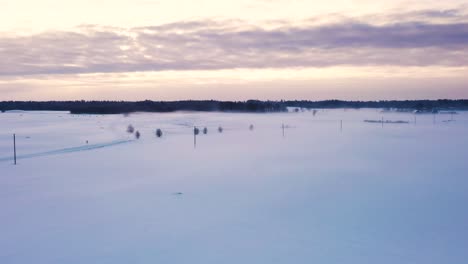 Cold-rural-scenic-snow-covered-countryside-road-winter-landscape-aerial-view-at-sunrise