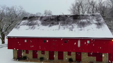 Aerial-reveal-of-red-barn-during-snowstorm