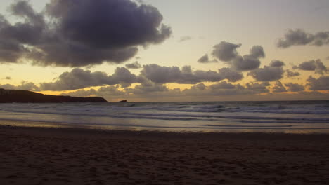 Colourful-sunset-on-Fistral-Beach,-a-yellow-horizon-melts-into-a-purple-skyline