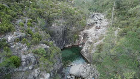 Aerial-flying-towards-Portela-do-Homem-Cascade,-fresh-water-stream-on-Rocks,-Tilt-down