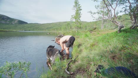 Man-And-Dog-Took-A-Break-By-Cleaning-Up-On-The-Lake-In-Ånderdalen-National-Park-In-The-Island-of-Senja,-Norway