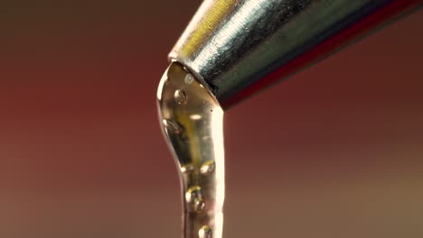 Macro-extreme-close-up-hot-glue-dripping-out-from-metal-nozzle