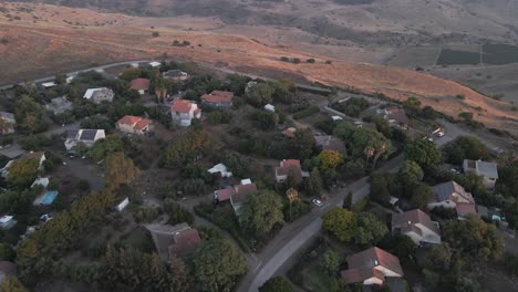 Aerial-view-over-a-hilltop-neighborhood-in-the-Golan-Heights,-dusk-in-Israel---tilt,-drone-shot