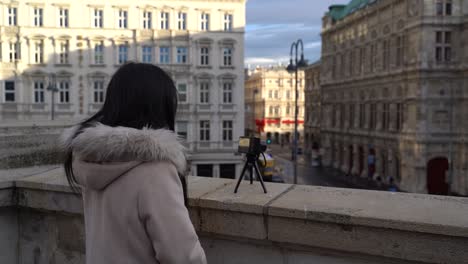 Female-solo-tourist-using-small-camera-on-tripod-to-film-city-scenery