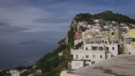Luft--Und-Panoramablick-Auf-Das-Dorf-Capri,-Die-Piazzetta,-Das-Meer,-Den-Vesuv-Und-Boote,-Die-An-Einem-Sonnigen-Tag-Mit-Einigen-Wolken-Vorbeifahren