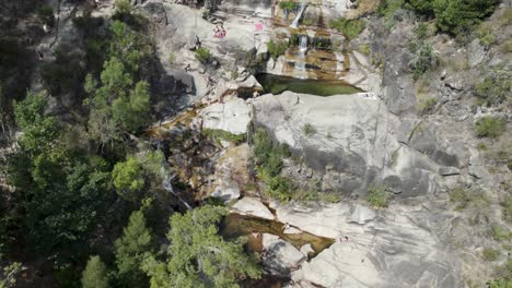 Aerial-circular-view-over-people-sunbathing-on-rocks,-at-waterfall-Fecha-de-Barjas