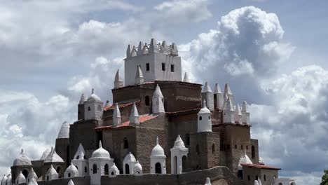 Tilting-up-medium-shot-of-the-large-incredible-Castle-"Zé-dos-Montes"-built-by-Jose-by-hand-with-bricks-from-instructions-by-God-in-Rio-Grande-do-Norte,-Brazil-on-a-warm-sunny-cloudy-day