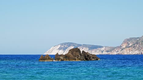 Blue-Ocean-With-Waves-Crashing-On-Rocks-In-Agia-Eleni-Beach,-Kefalonia,-Greece---wide-shot