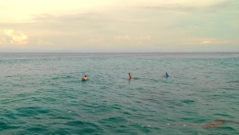 Surfistas-En-La-Playa-De-Bali,-Indonesia-Esperando-La-Ola-Perfecta-Para-Montar-En-Una-Puesta-De-Sol---Disparo-De-Drones