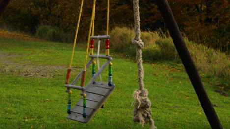 Child's-colored-swing-made-of-wood-hanging-on-a-construction-moves-during-strong-wind-to-the-side-during-a-sunny-autumn-day-captured-in-Beskids-area-4k-60fps