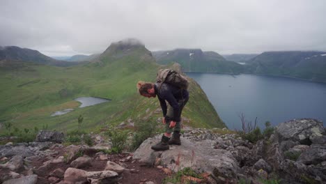 A-Male-Backpacker-Taking-Break-On-A-Rocky-Plateau-With-Beautiful-Mountain-Lake-View-At-The-Background,-Segla,-Senja-Island,-Norway
