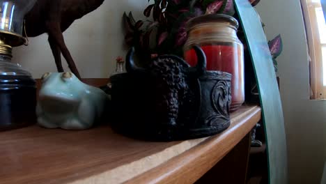 Dark-bowl-with-a-bul-head-on-it-itting-on-a-shelf-with-out-asorted-objects