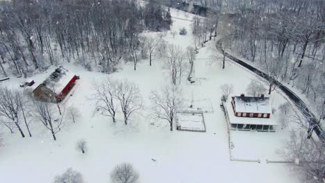 Aerial-truck-shot-of-large-home-and-barn-estate-during-winter-snow-storm