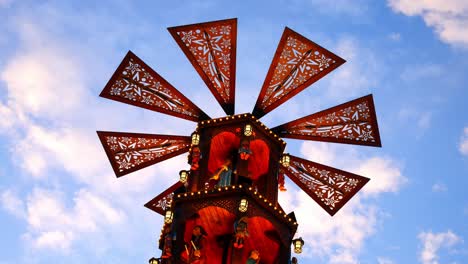 Weihnachtsmarkt-Festlich-Beleuchtete-Rotierende-Karussellwindmühle-Gegen-Den-Blauen-Himmel-Vorbeiziehende-Wolken