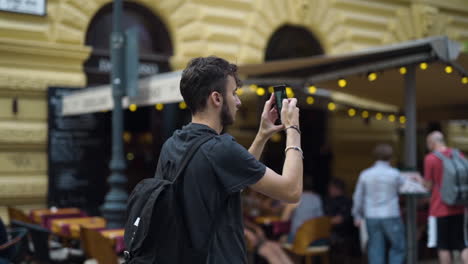 Male-tourist-rises-phone-to-take-pictures-of-Budapest-with-blurred-background