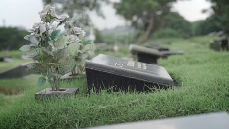 Placa-Conmemorativa-De-Granito-Negro-En-El-Cementerio-Y-Jarrón-Con-Flores-Artificiales,-Cerrar