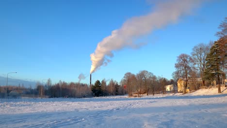 White-smoke-coming-out-of-a-tall-chimney-on-a-cold-sunny-winter-day-with-a-clear-blu-sky