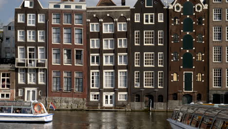 Canal-with-taxi-boat-passing-in-Amsterdam,-The-Netherlands