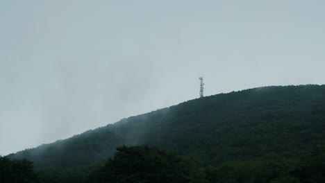 An-antenna-is-seen-on-top-of-a-mountain-during-a-cloudy-day