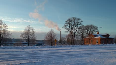 White-smoke-coming-out-of-a-tall-chimney-on-a-cold-sunny-winter-while-cars-are-driving-by