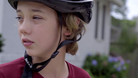 Cute-boy-wearing-a-bike-helmet-looks-to-his-right-in-slow-motion,-close-up