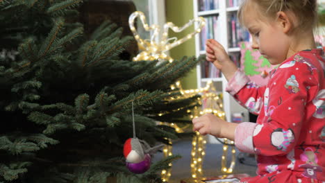 A-closeup-of-a-little-girl-decorates-a-pine-Christmas-tree-with-ornaments