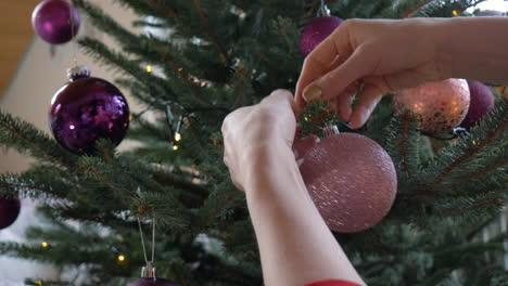 Closeup-of-a-pair-of-hands-putting-an-ornament-on-a-Christmas-Tree