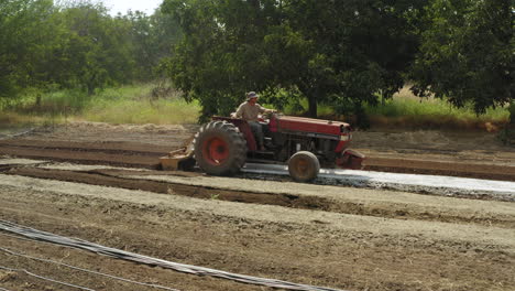Farmer-driving-a-vintage-tractor-in-slow-motion,-profile-view-of-agricultural-machine-making-furrows