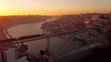 Drohnenaufnahmen-Aus-Der-Luft-Bei-Sonnenuntergang-Von-Porto-Stadt-Portugal-Goldene-Stunden-Brücke-über-Den-Douro-Fluss-Elektrische-Straßenbahn-Durchqueren-Die-Stadt-Und-Den-Malerischen-Vogelflug