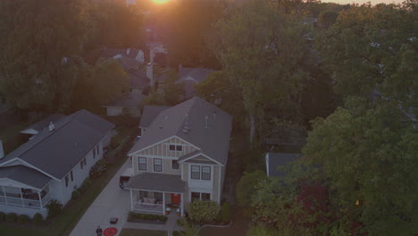 Descent-towards-house-in-suburbia-with-drone-op-in-driveway-at-sunset