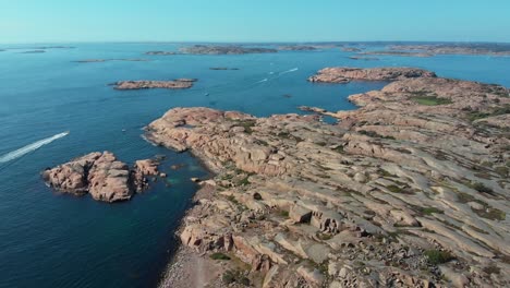 Scattered-Rock-Islets-In-The-Ocean-Of-Stångehuvud-And-A-Speedboat-On-A-Sunny-Day---Aerial-Shot