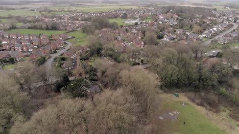 Aerial-pull-back-view-above-UK-Church-spire-in-British-small-residential-countryside-farming-village