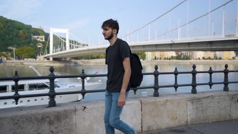 Young-traveler-walking-along-the-Danube-river-in-Budapest-with-Elisabeth-Bridge-in-background