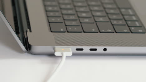 Close-up,-person-plugging-in-magsafe-charger-to-new-M1-MacBook-Pro