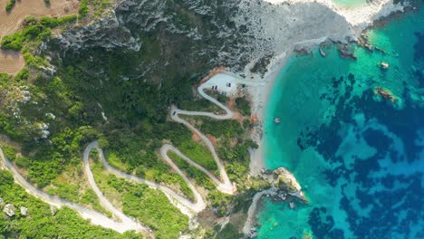 Top-down-view-idyllic-natural-scenery,-Emerald-water-and-zigzag-road,-Agia-Eleni-beach