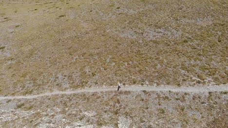 AERIAL-shot-of-a-man-walking-,-hiking-alone-at-Kissavos-Greek-mountain-at-Thessaly-region-,-drone-view,-route-at-mountain-,-sport-life-style-,-healthy-way-of-leaving-brown-landscape-trekking