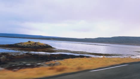 POV-Ansicht-Perspektive-Von-Island-Straße-Mit-Schwarzem-Sandstrand,-Arktischem-Meer-Auf-Der-Linken-Seite-Und-Bewölktem-Himmel-Im-Herbst