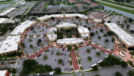 Wide-aerial-pan-of-busy-outdoor-shopping-plaza---slow-tracking-pan-with-view-of-parking-lot