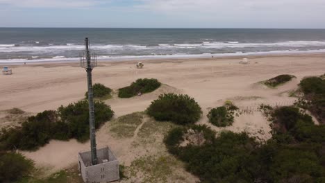 Aerial-shot-of-Telecommunication-Tower-in-front-of-sandy-beach-and-Atlantic-Ocean-during-sunlight
