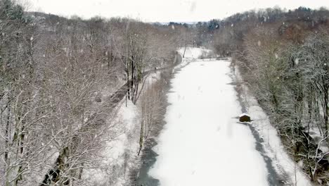 Aerial-establishing-shot-of-frozen-lake,-pond-during-winter-snowfall