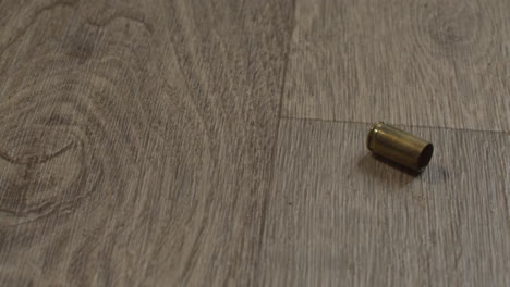 Fired-9mm-shell-casing-falling-on-a-hardwood-living-room-floor