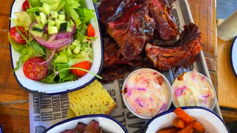 Beef-brisket-with-salad,-pork-ribs-with-sweet-potato-fries,-cornbread-and-coleslaw,-traditional-american-food,-4K-top-view-shot