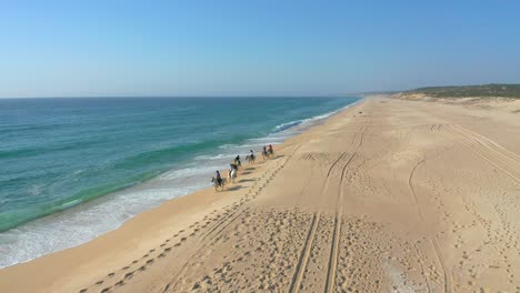 Aerial-view-of-horse-expedition-in-the-beach-with-unrecognizable-people,-Melides-Portugal
