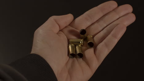 Hand-opening-and-revealing-9mm-bullet-shell-cases