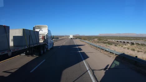 POV-While-driving-along-the-Interstate-and-passed-by-two-tractor-trailers-in-western-Texas-in-a-sunny-day