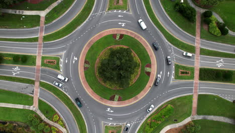 Top-down-view-of-cars-driving-around-traffic-circle---rotating-aerial-shot