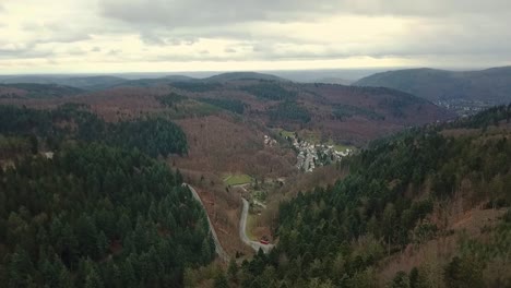 Aerial-view-of-road-cutting-through-beautiful-mountainous-valley,-Odenwald-Germany