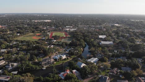Aerial-Shot-of-Tropical-Florida-Neighborhood-With-Football-Field-Near-Bayou
